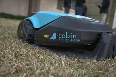 Robotic lawn mower beside a boundary wire on a lush green lawn