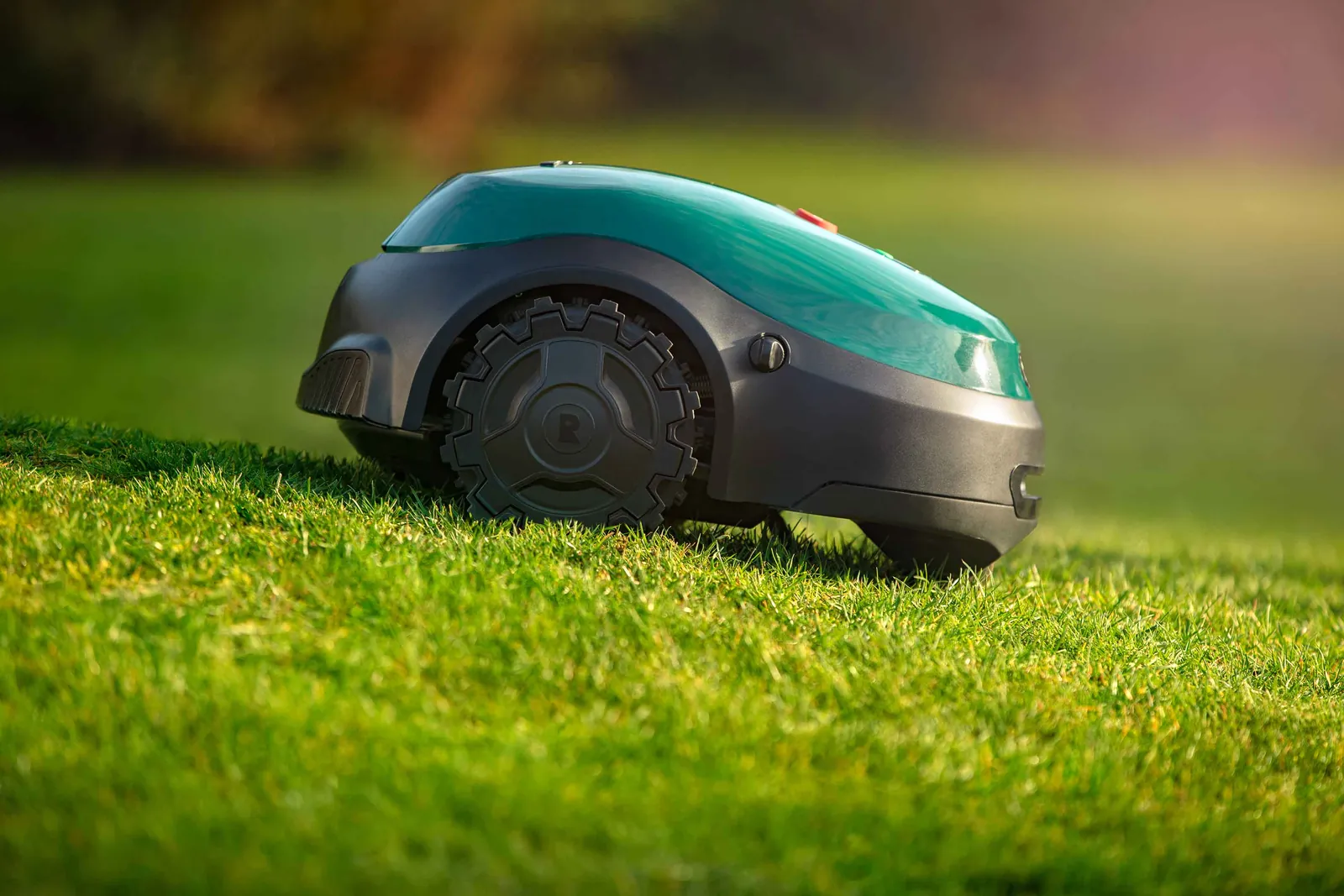 Robotic mower with deep-tread wheels climbing wet slope